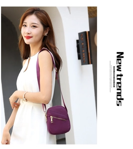 Detail shot of purple nylon crossbody bag with gold zippers worn with white dress