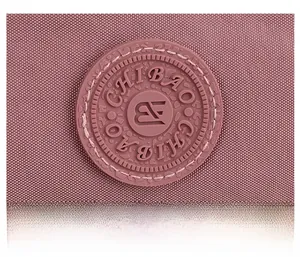 Close-up of pink nylon fabric texture and circular logo detail on a crossbody bag