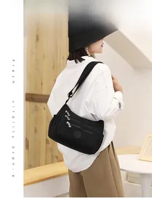 Close-up of a black nylon crossbody bag featuring multiple zipper pockets and wide strap