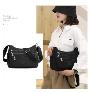 Detail of black nylon crossbody bag with multi-layer zipper pockets and adjustable strap