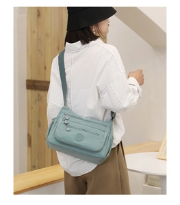 Detail of mint green nylon crossbody bag showing multiple pockets and adjustable strap