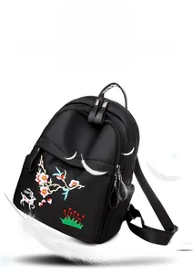 Détail d'une broderie florale colorée sur un sac à dos léger en nylon noir de qualité
