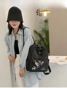 Détail de la broderie cerf blanc et fleur rouge sur un sac à dos en nylon noir