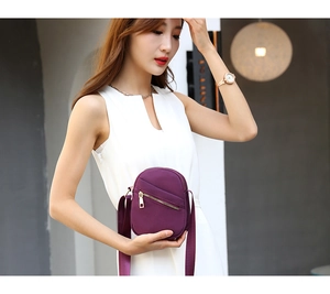 Detail of a purple nylon crossbody bag with metal zipper and adjustable strap