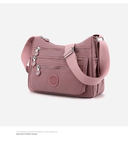 Detailed close-up of dusty pink nylon crossbody bag showing multiple zippered pockets and strap