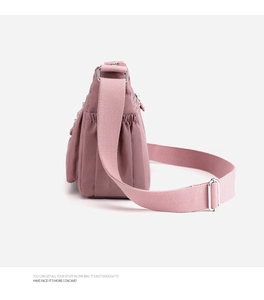 Detail view of nylon crossbody bag featuring side pleated pocket and wide shoulder strap