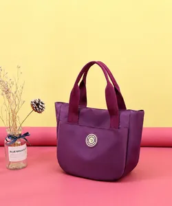 Détail macro du sac à main en nylon violet avec logo métallique rond et poche avant