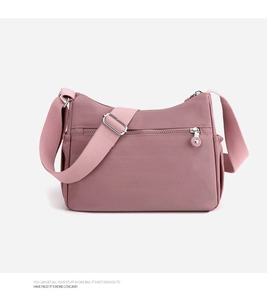 Detail of pink nylon crossbody bag featuring water-resistant fabric and adjustable strap