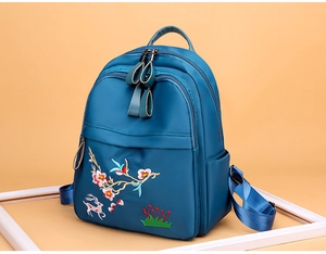 Détail de broderie de fleurs de prunier et cerf sur sac à dos bleu paon étanche