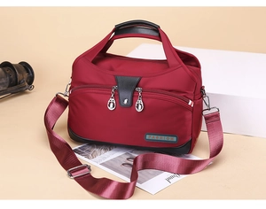 Detail of red water-resistant oxford fabric crossbody bag with black leather stitching