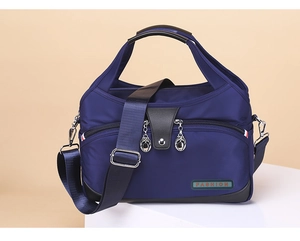 Detail of waterproof navy blue nylon bag with leather handles and fashion logo plaque