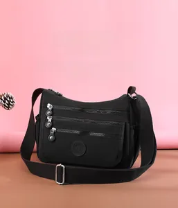 Detail of nylon crossbody bag showing multiple zippered pockets and adjustable shoulder strap