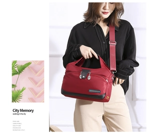 Detail of burgundy oxford fabric bag showing multi-zip compartments and wide shoulder strap