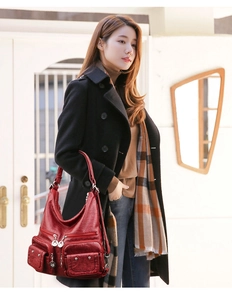 Close-up of a soft red leather shoulder bag with metallic rivets and multi-pocket texture