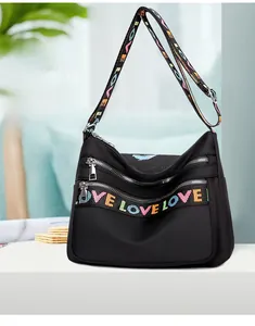 Detail of black nylon crossbody bag featuring colorful LOVE letter strap and multiple pockets