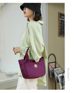 Détail du sac cabas en nylon violet avec poignée renforcée et emblème doré de marque