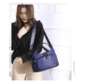 Detail of blue waterproof oxford shoulder bag featuring multiple zipper pockets and wide strap