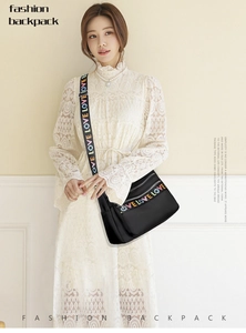 Close-up of black oxford crossbody bag featuring colorful LOVE embroidery and rainbow strap