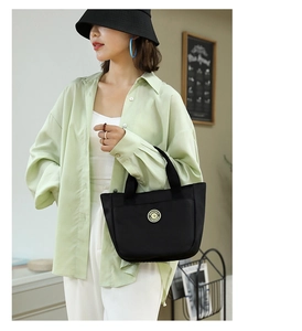 Détail d'un grand sac cabas en nylon noir avec logo circulaire et style urbain décontracté