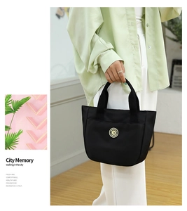 Détail du sac cabas en nylon noir avec emblème doré sur un sac à main chic décontracté