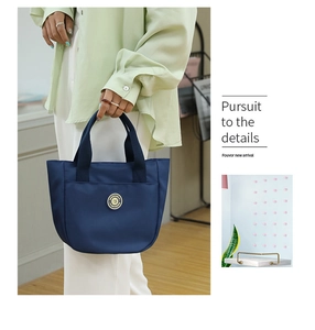 Détail d'un sac cabas en nylon bleu marine avec logo en métal et poignées tissées chic