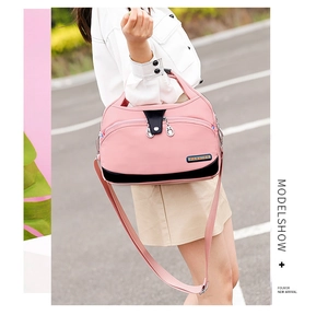 Pink waterproof nylon handbag with black bottom panel shown on a model outdoors