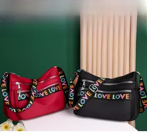 Macro shot of nylon crossbody bags with multi-zipper pockets and colorful LOVE webbing