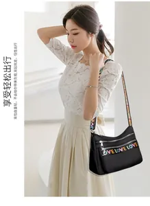 Detail of multi-pocket black oxford crossbody bag with colorful LOVE letter straps
