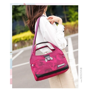 Outdoor model shot of pink camo waterproof oxford bag with crossbody strap and handle