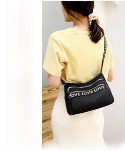 Detail of waterproof nylon crossbody bag with rainbow LOVE embroidery and multiple zippers