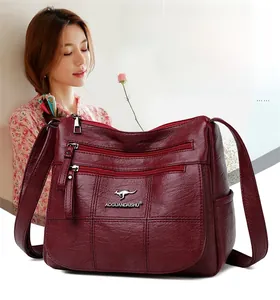 Macro detail of wine red pebbled leather shoulder bag with three-tier zipper structure