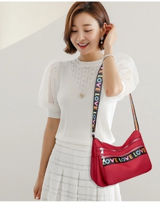 Detail of burgundy nylon crossbody bag with three zippers and colorful LOVE webbing strap