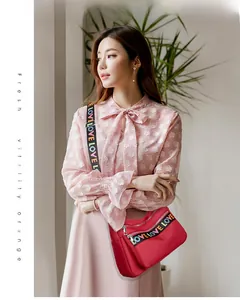 Detail of red oxford crossbody bag featuring a colorful LOVE letter print wide strap