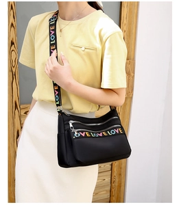 Detail of black oxford crossbody bag featuring colorful LOVE letter print and metal zippers