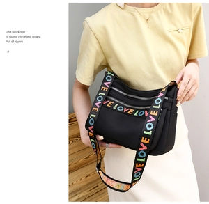 Detail of black multi-pocket crossbody bag featuring colorful LOVE letter wide strap