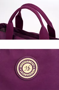 Détail du sac en nylon violet avec poignées tissées épaisses et logo circulaire