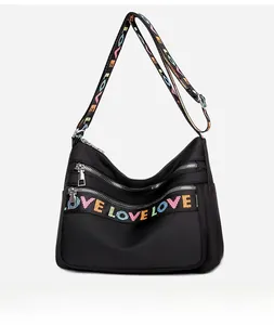 Close-up of waterproof black nylon crossbody bag with multi-zipper layers and LOVE webbing