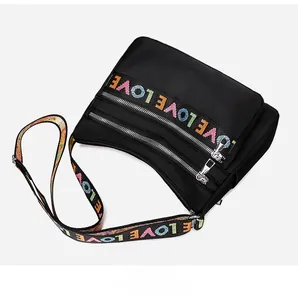 Detail of colorful LOVE embroidery on black nylon shoulder bag with silver zippers