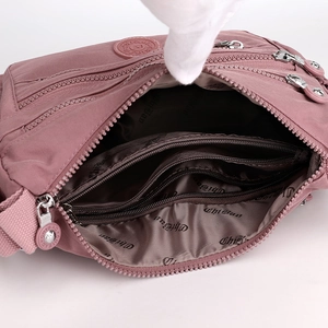 Multifunctional dusty rose nylon crossbody bag featuring multiple zipper compartments