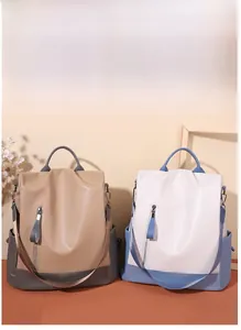 Detail of color-block PU leather backpack showing front zipper pockets and side storage