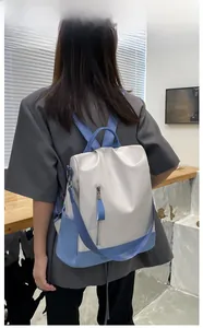 Rear view of a two-tone PU leather backpack with side zippers shown on a model