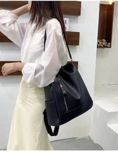 Detail view of black PU leather backpack with vertical zipper and soft texture on model