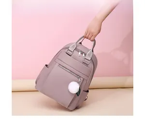 Détail du sac à dos en nylon lavande avec poignée renforcée et breloque boule en peluche