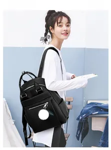 Détail d'un sac à dos noir en tissu Oxford avec fermetures éclair et pompon décoratif