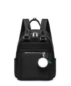 Détail du sac à dos en tissu Oxford noir avec zips argentés et pompon blanc décoratif