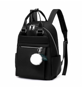 Vue détaillée du sac à dos en nylon noir avec fermetures éclair et pompon blanc décoratif