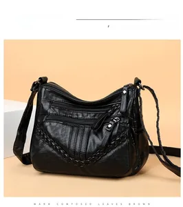 Detail of black PU leather crossbody bag featuring three-tier zippers and woven trim