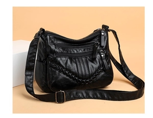 Detail view of black PU leather crossbody bag featuring triple zippers and woven trim