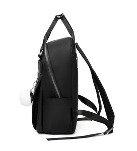 Vue latérale du sac à dos en tissu Oxford noir avec pompon blanc et charme de feuille