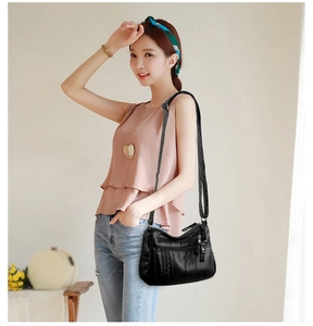 Detail of a soft black PU leather multi-zipper crossbody bag with intricate woven texture
